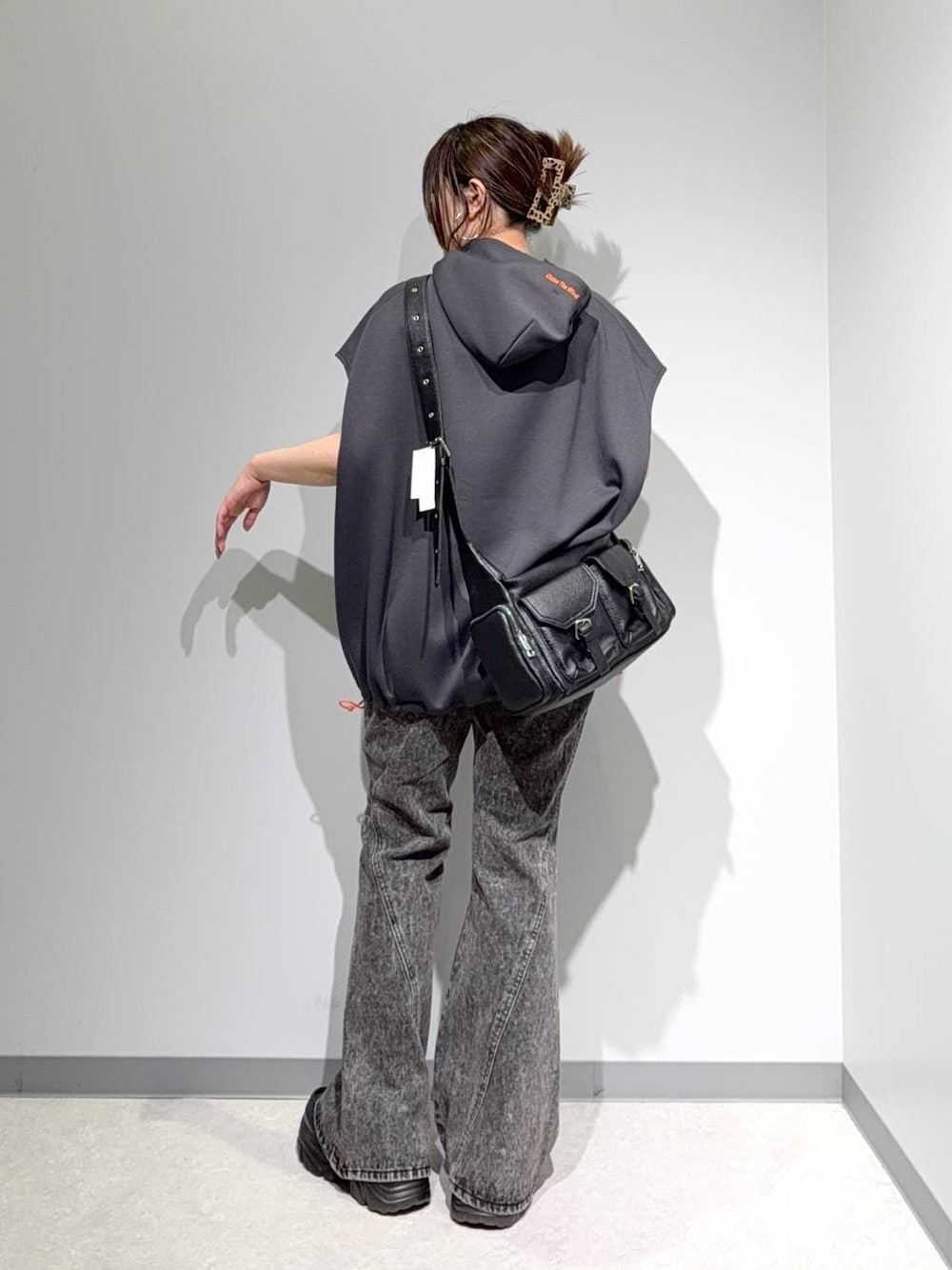 グレー系のベスト、ブラック系のデニムパンツ、ブラック系のショルダーバッグを着用したレディースの夏コーディネートの1枚目の写真