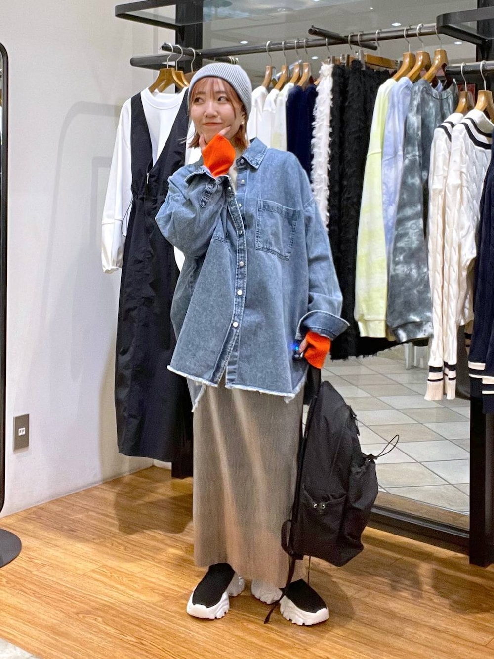 グレー系のスカート、ブラック系のバックパック/リュック、ブルー系のシャツ/ブラウスを着用したレディースの冬コーディネートの1枚目の写真