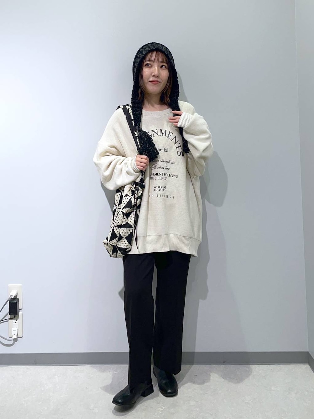 ブラック系のスラックス、その他のトートバッグ、ホワイト系のニット/セーターを着用したレディースの秋コーディネートの1枚目の写真