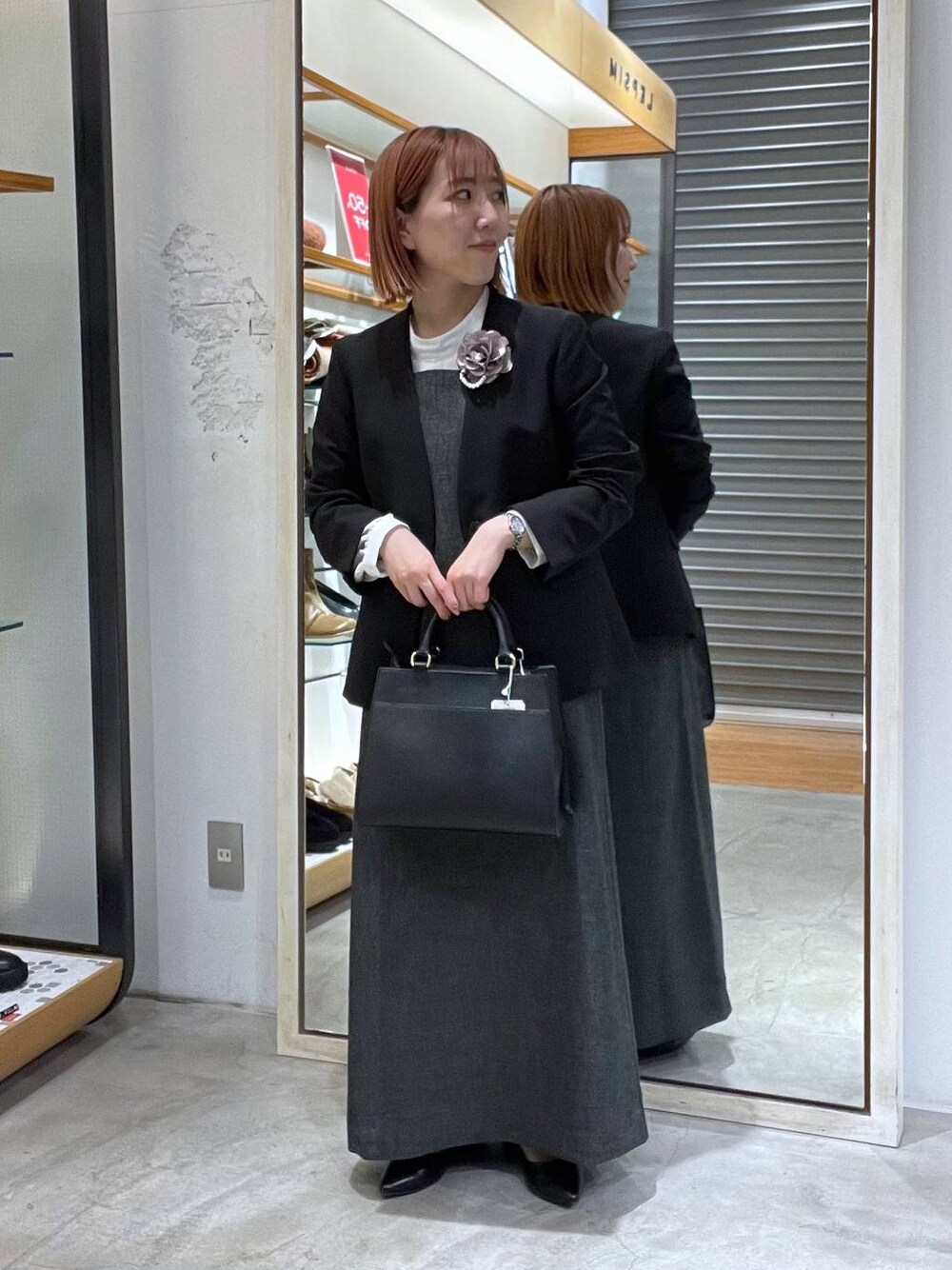 ブラック系のノーカラージャケット、ホワイト系のシャツ/ブラウス、ブラック系のショルダーバッグを着用したレディースの冬コーディネートの1枚目の写真