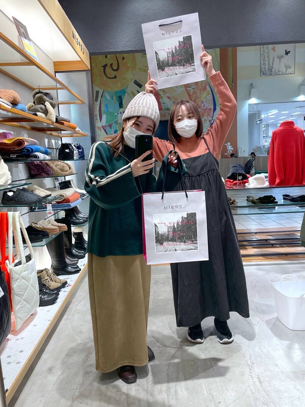 オレンジ系のニット/セーター、ベージュ系のスカート、グレー系のワンピースを着用したレディースの冬コーディネートの1枚目の写真