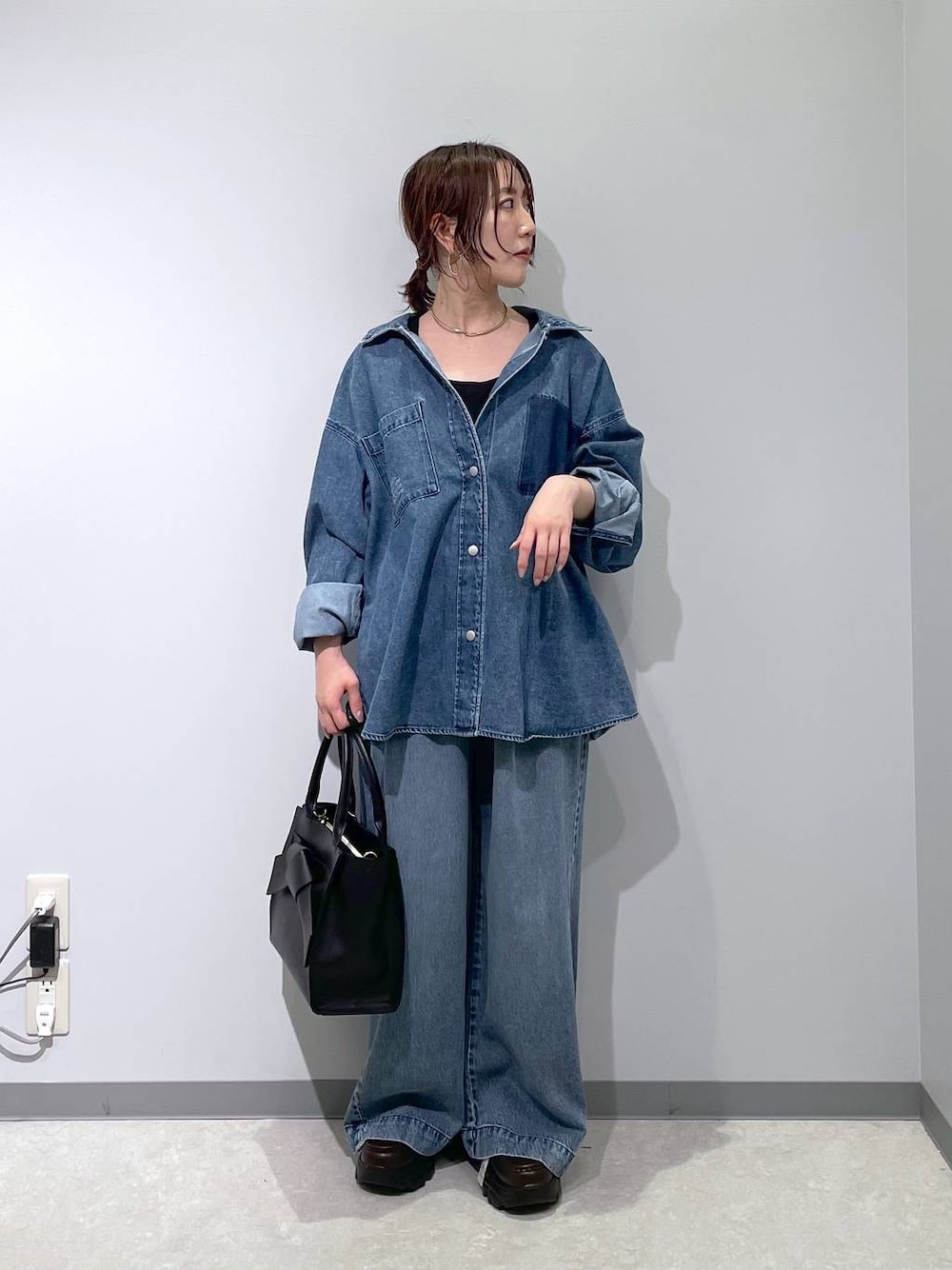 ブルー系のデニムパンツ、ブラック系のハンドバッグ、ブラウン系のローファーを着用したレディースの冬コーディネートの1枚目の写真