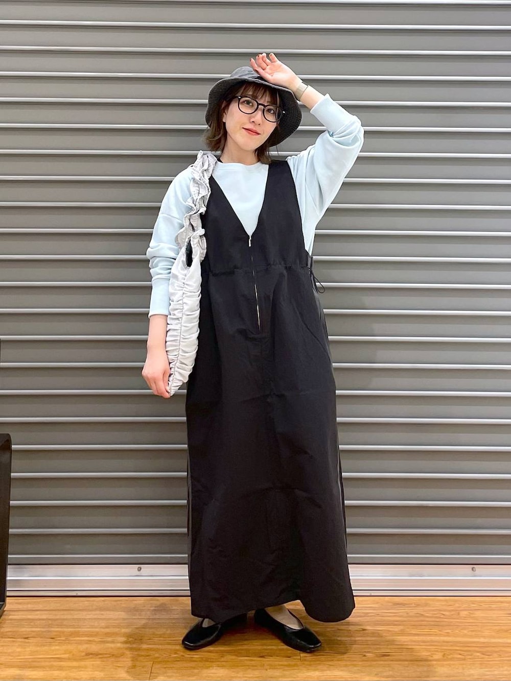 シルバー系のトートバッグ、ブラック系のパンプス、ブラック系のジャンパースカートを着用したレディースの春コーディネートの1枚目の写真
