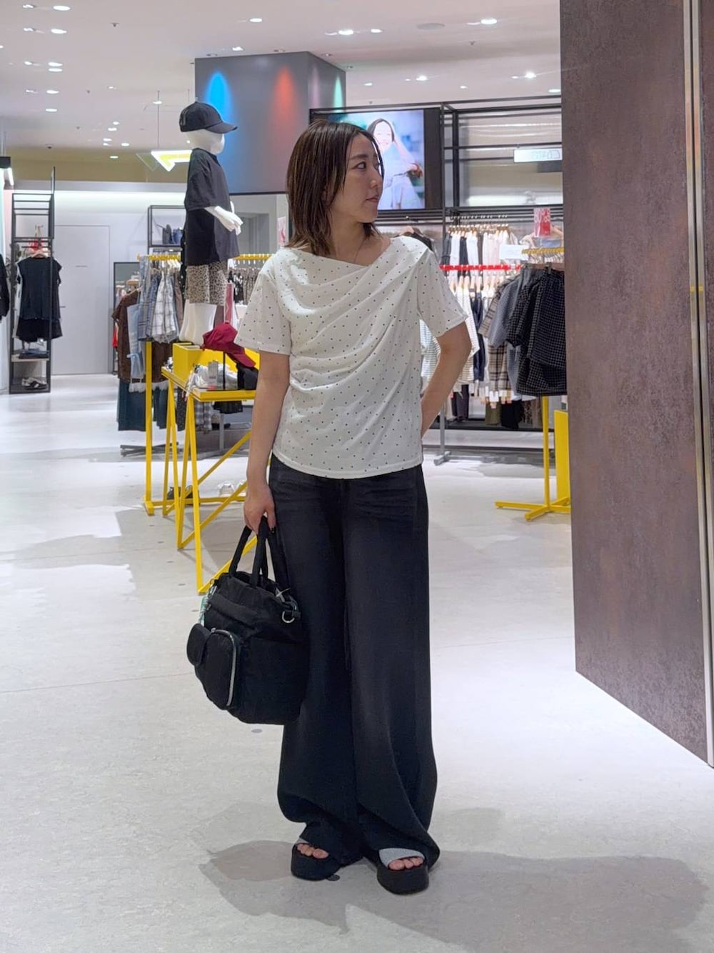 ブラック系のデニムパンツ、ベージュ系のTシャツ/カットソー、ブラック系のトートバッグを着用したレディースの夏コーディネートの1枚目の写真