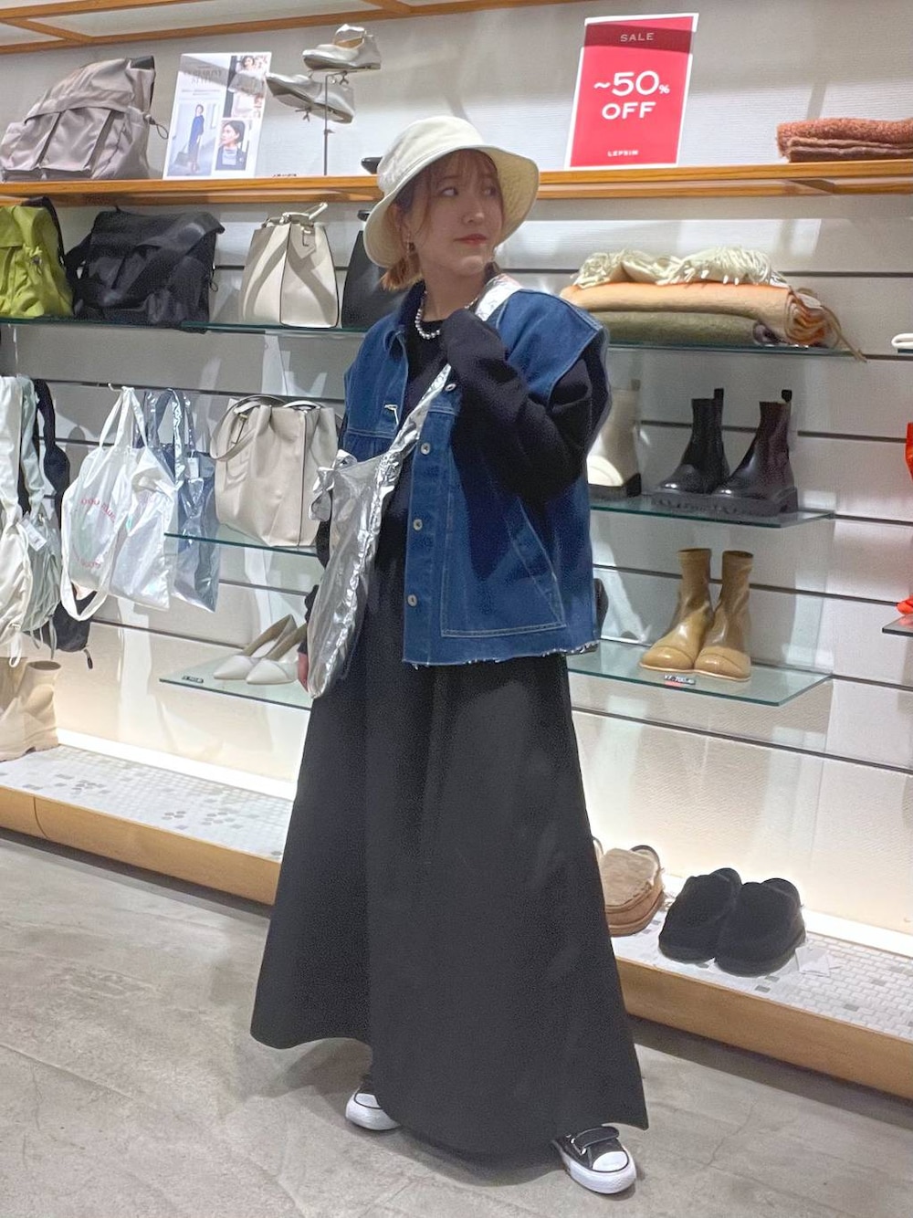 ブラック系のワンピース、シルバー系のトートバッグ、ブルー系のベストを着用したレディースの春コーディネートの1枚目の写真