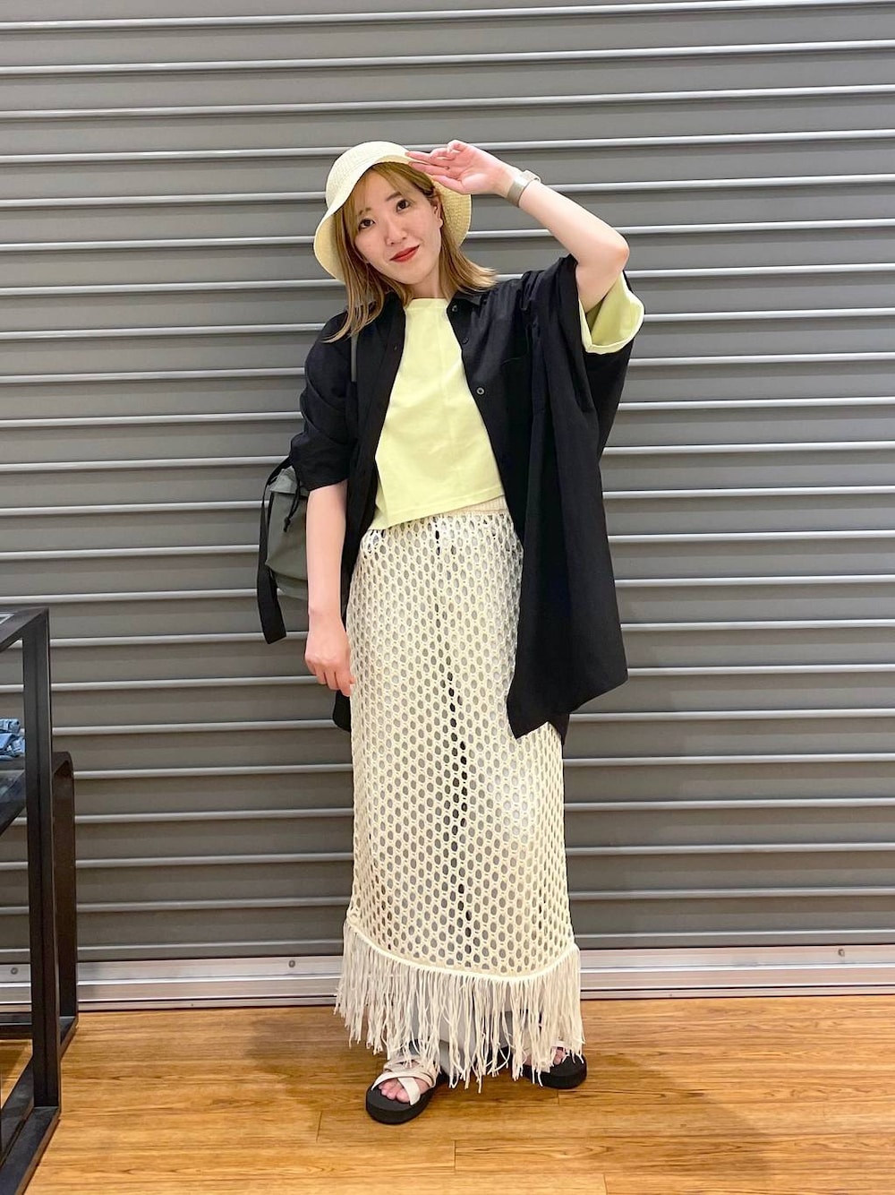 グリーン系のショルダーバッグ、ブルー系のデニムパンツ、ブラック系のチュニックを着用したレディースの夏コーディネートの1枚目の写真