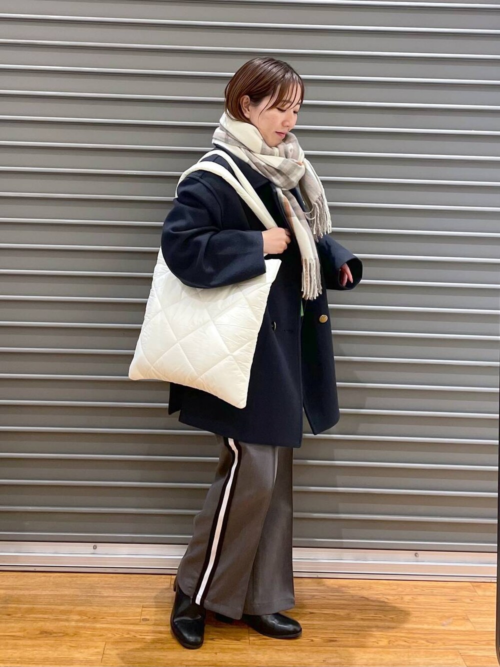 ブラック系のブーツ、ホワイト系のトートバッグ、グレー系のその他パンツを着用したレディースの秋コーディネートの1枚目の写真