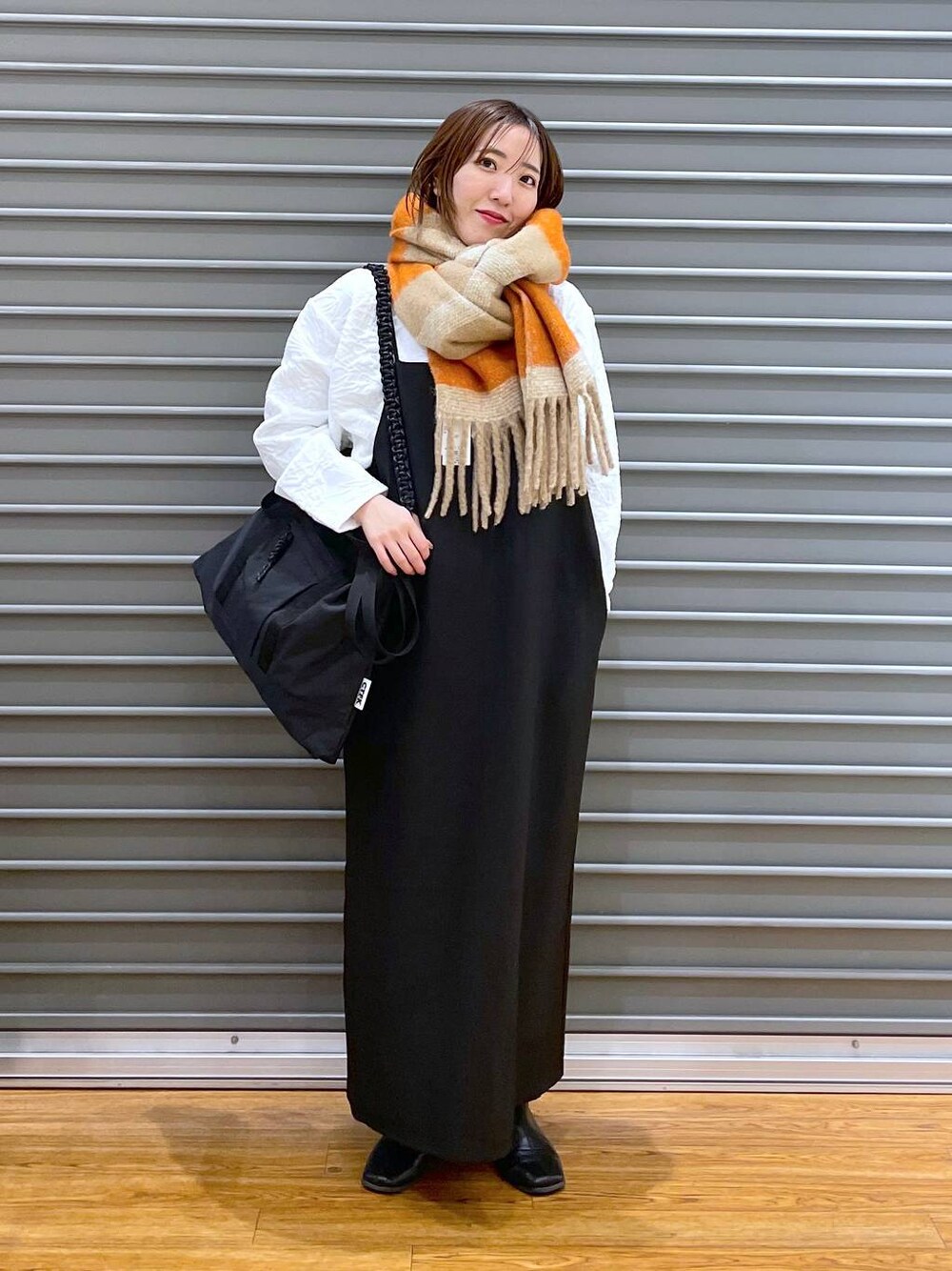 ブラック系のワンピース、ブラック系のショルダーバッグ、ホワイト系のTシャツ/カットソーを着用したレディースの冬コーディネートの1枚目の写真