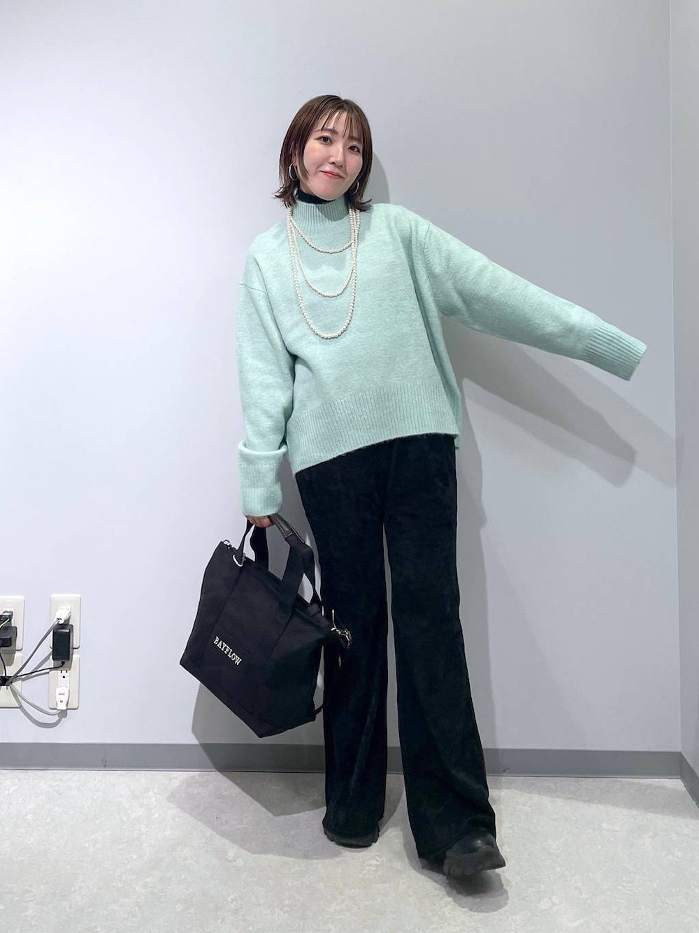 グリーン系のニット/セーター、ブラック系のその他パンツ、ブラック系のトートバッグを着用したレディースの冬コーディネートの1枚目の写真