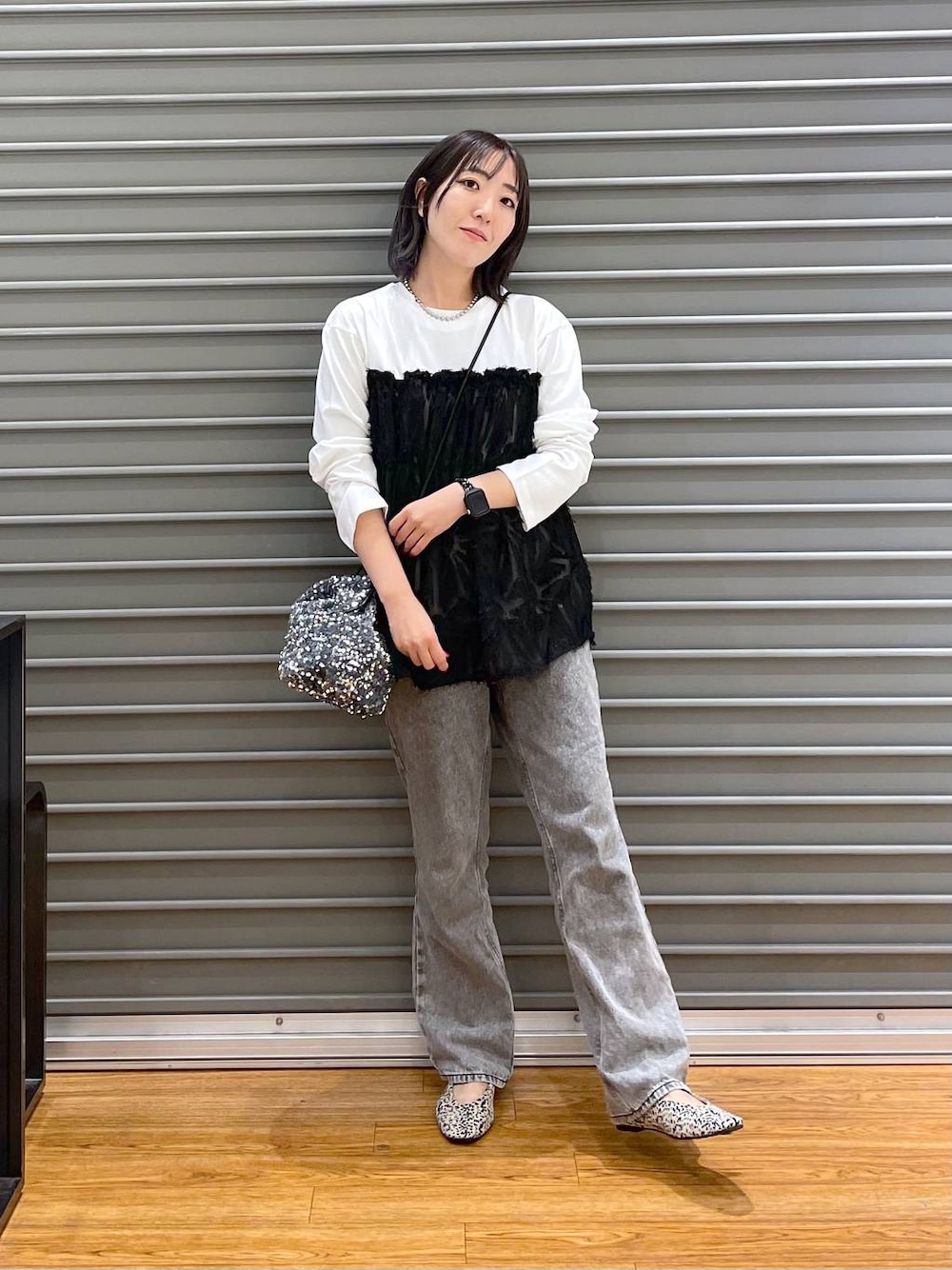シルバー系のショルダーバッグ、ホワイト系のパンプス、グレー系のデニムパンツを着用したレディースの秋コーディネートの1枚目の写真