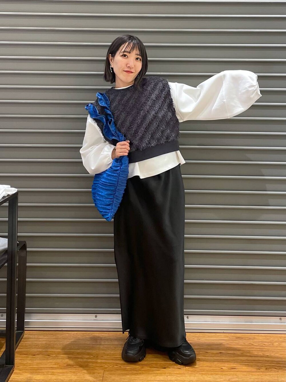 グレー系のベスト、ブラック系のスカート、ホワイト系のTシャツ/カットソーを着用したレディースの春コーディネートの1枚目の写真