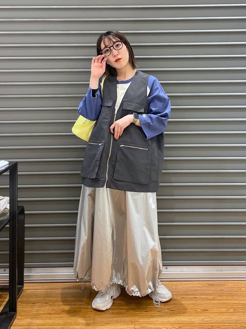 イエロー系のショルダーバッグ、ブルー系のTシャツ/カットソー、シルバー系のスカートを着用したレディースの春コーディネートの1枚目の写真