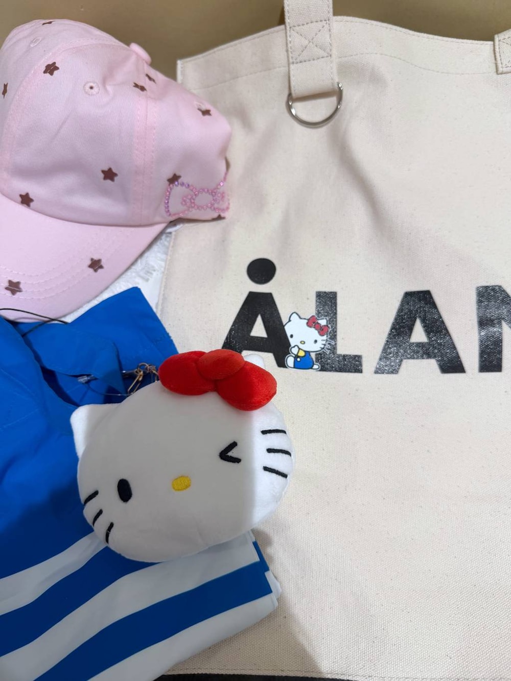 ホワイト系のトートバッグ、ピンク系のキャップを着用したレディースの夏コーディネートの1枚目の写真