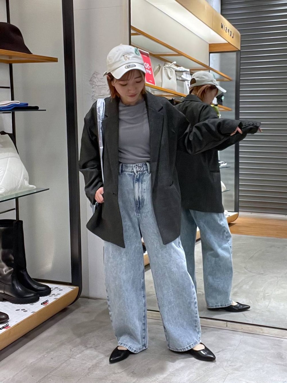 ブルー系のデニムパンツ、ブラック系のテーラードジャケット、シルバー系のトートバッグを着用したレディースの春コーディネートの1枚目の写真