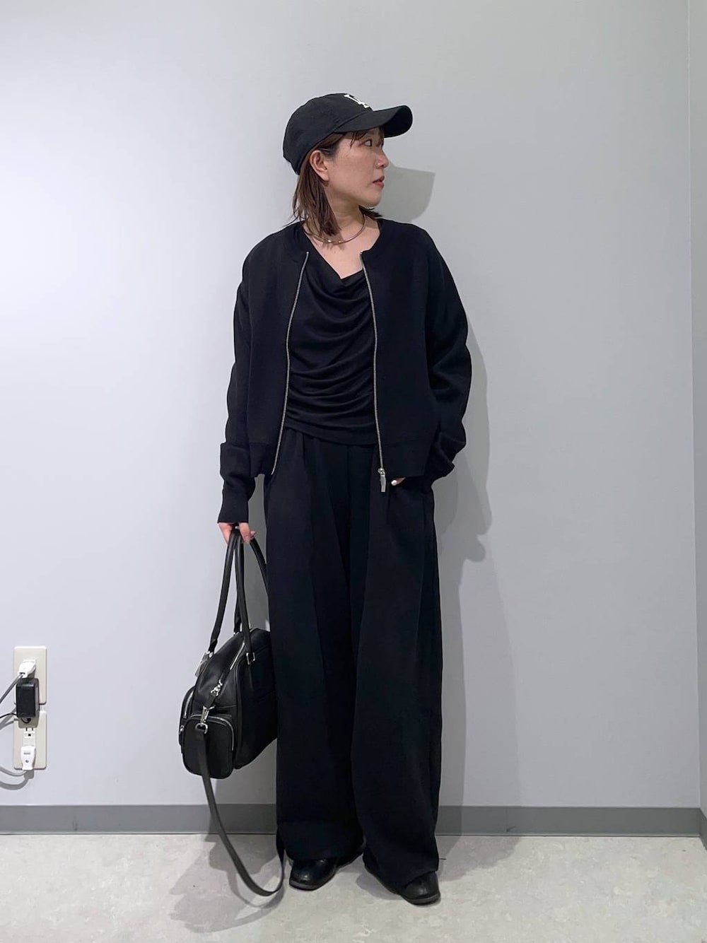 ブラック系のボストンバッグ、ブラック系のTシャツ/カットソー、ブラック系のカーディガン/ボレロを着用したレディースの冬コーディネートの1枚目の写真