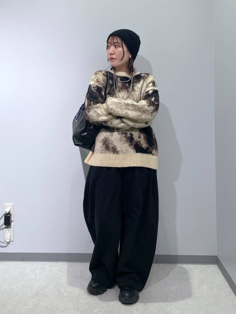 ブラウン系のニット/セーター、ブラック系のボストンバッグ、ブラック系のスウェットパンツを着用したレディースの冬コーディネートの1枚目の写真