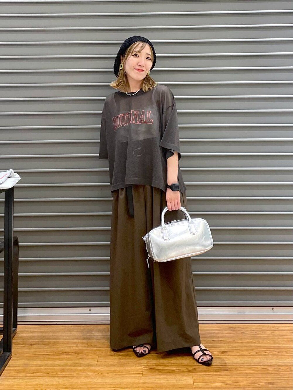 グレー系のその他トップス、ブラウン系のスラックス、シルバー系のボストンバッグを着用したレディースの夏コーディネートの1枚目の写真