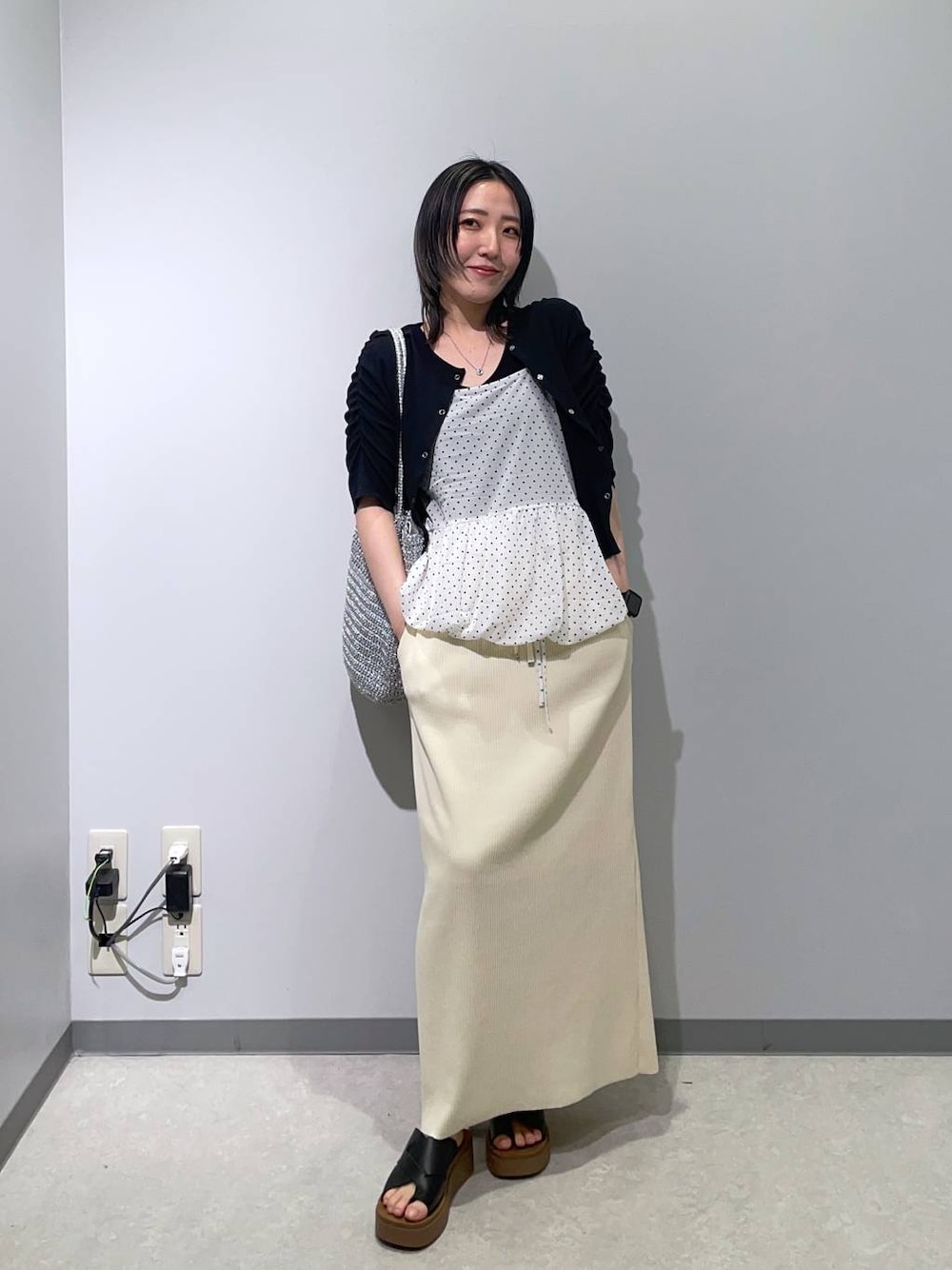 ブラック系のサンダル、ホワイト系のスカート、シルバー系のショルダーバッグを着用したレディースの春コーディネートの1枚目の写真