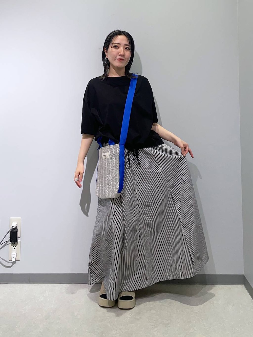 ブルー系のスカート、ホワイト系のサンダル、グレー系のトートバッグを着用したレディースの春コーディネートの1枚目の写真