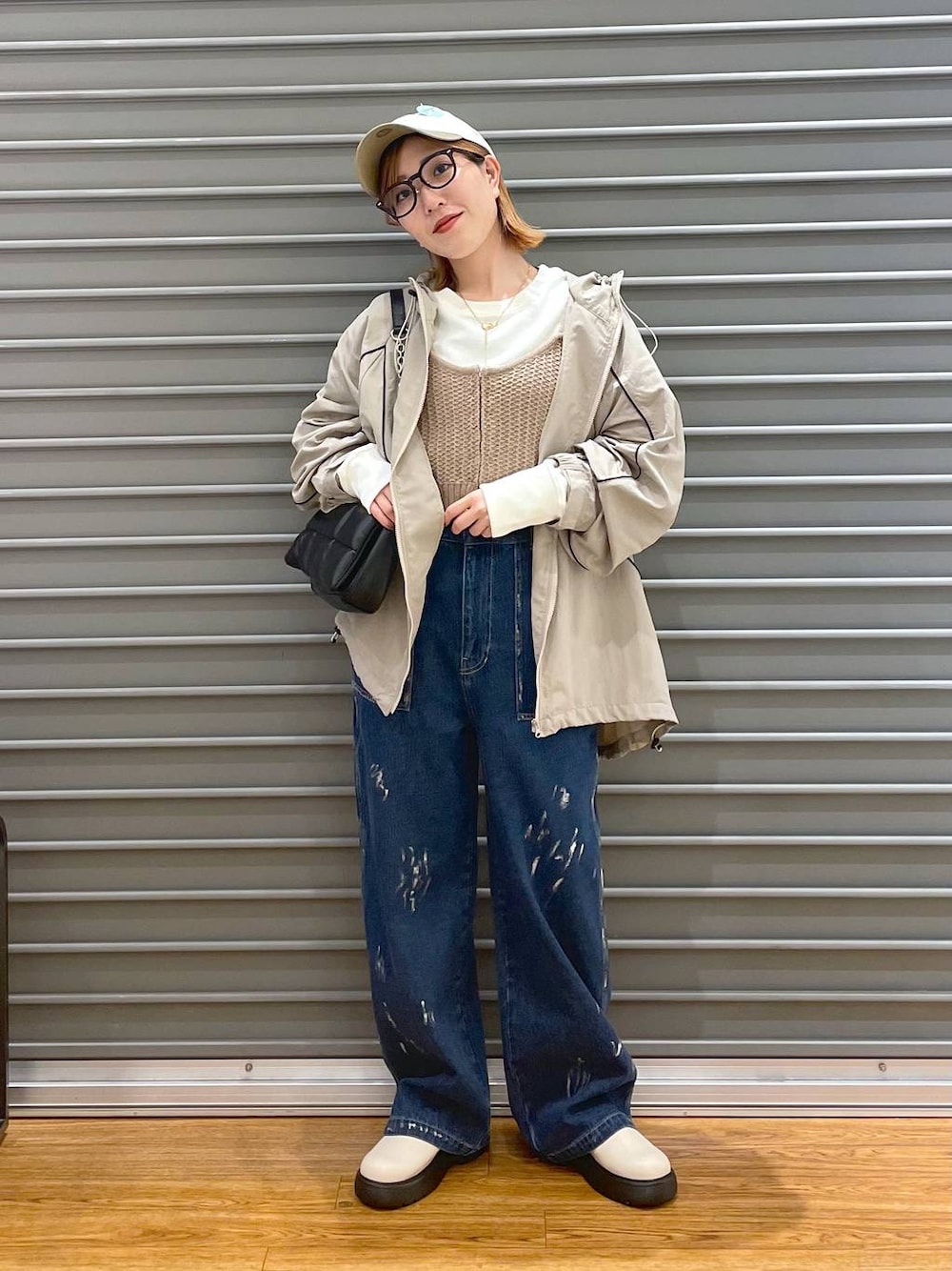 ブラック系のショルダーバッグ、ベージュ系のニット/セーター、ブルー系のデニムパンツを着用したレディースの春コーディネートの1枚目の写真