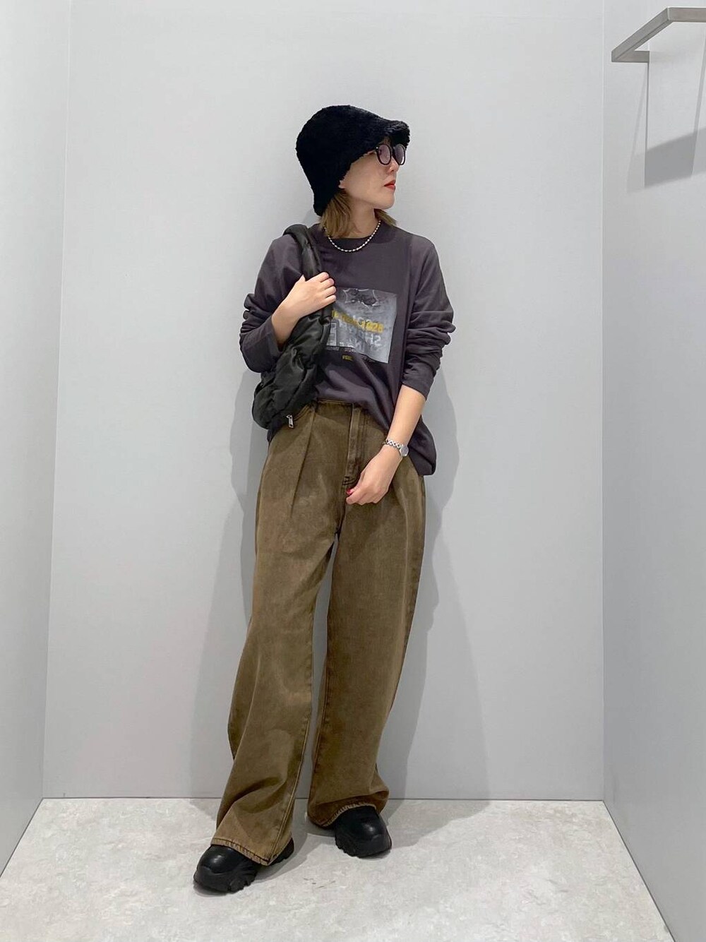ブラック系のハンドバッグ、ブラウン系のデニムパンツ、グレー系のTシャツ/カットソーを着用したレディースの秋コーディネートの1枚目の写真