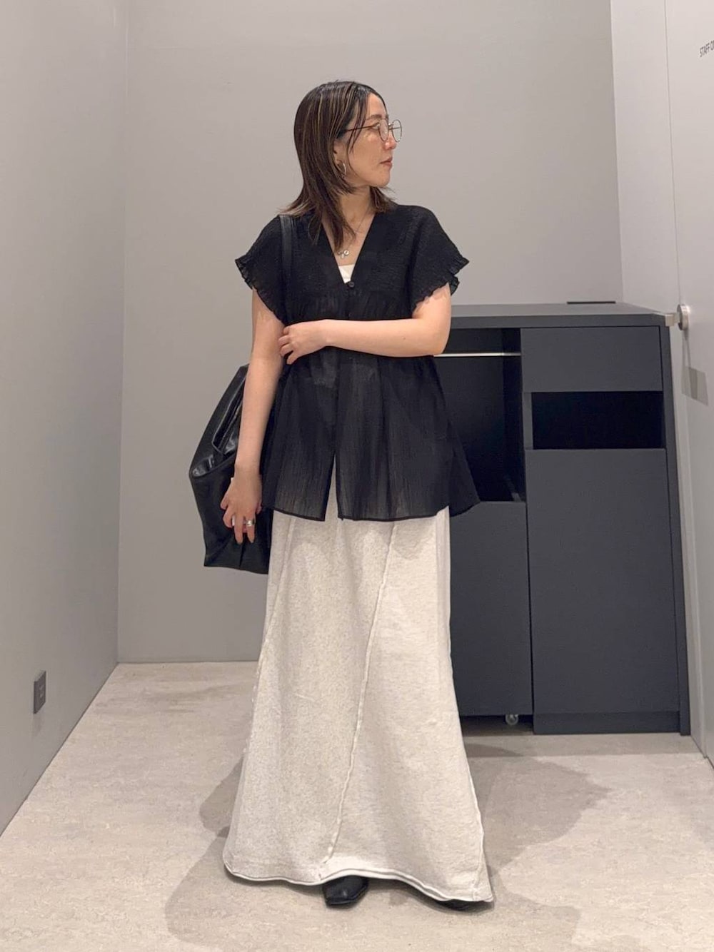 グレー系のスカート、ブラック系のショルダーバッグ、ブラック系のシャツ/ブラウスを着用したレディースの夏コーディネートの1枚目の写真