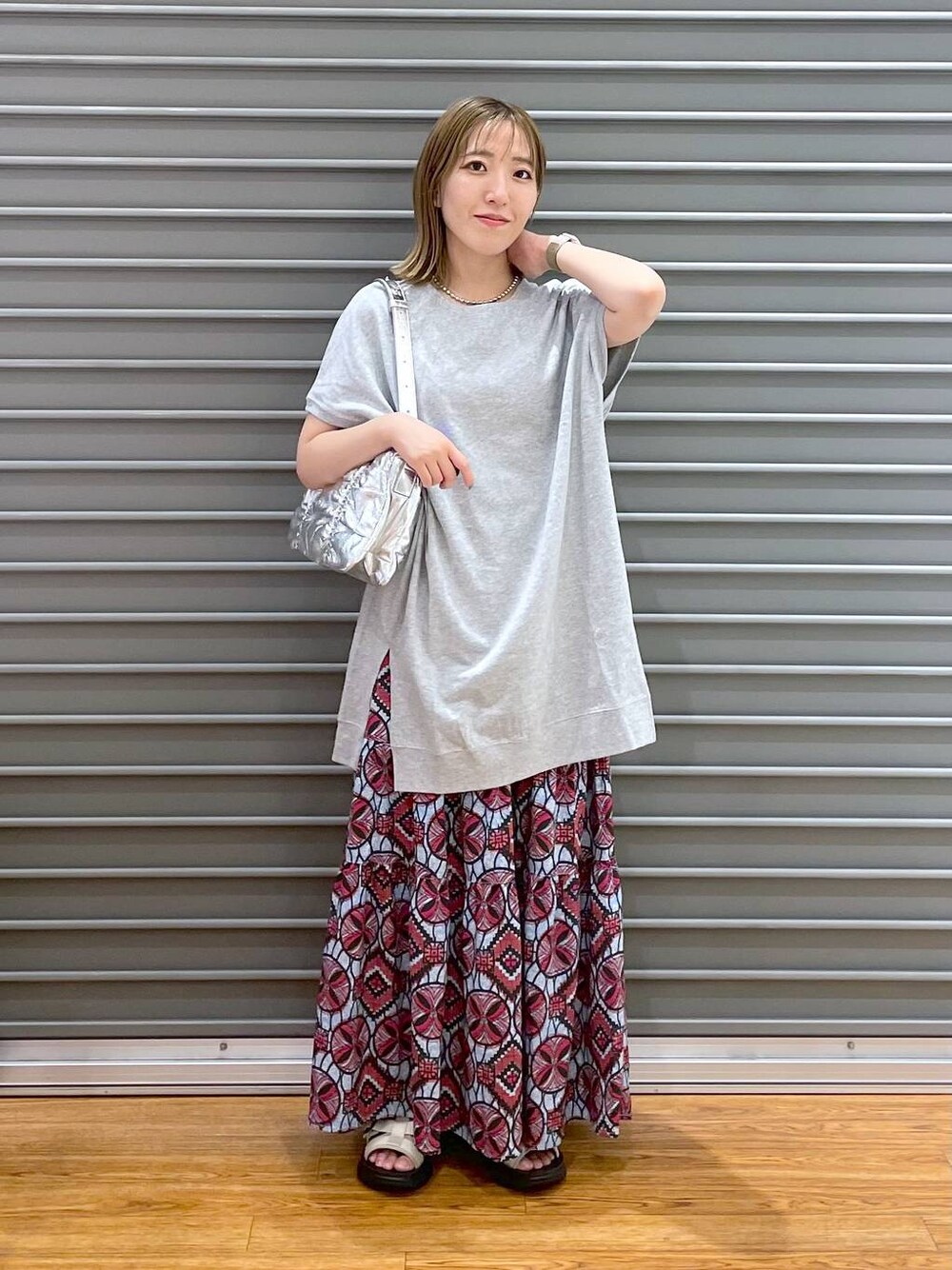 ピンク系のスカート、シルバー系のショルダーバッグ、ホワイト系のサンダルを着用したレディースの夏コーディネートの1枚目の写真
