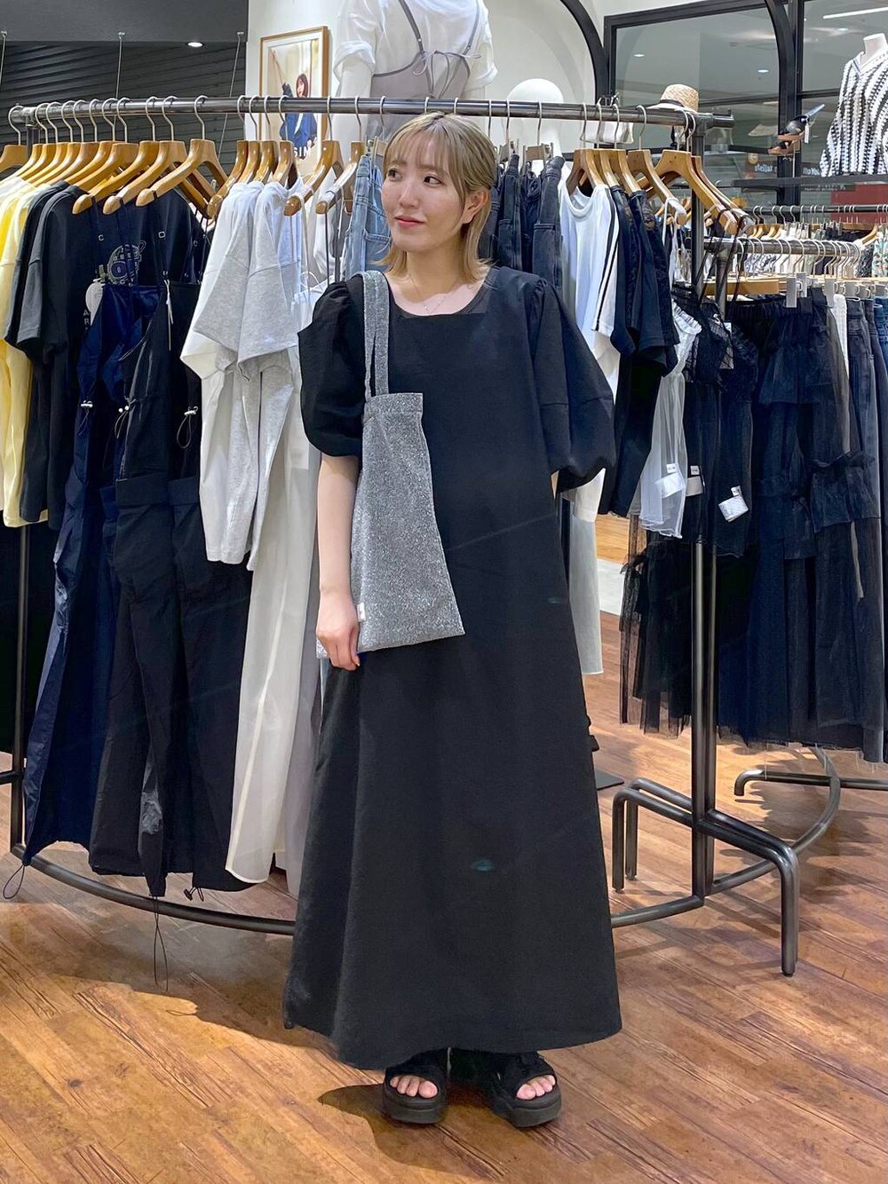 シルバー系のトートバッグ、ブラック系のワンピースを着用したレディースの夏コーディネートの1枚目の写真