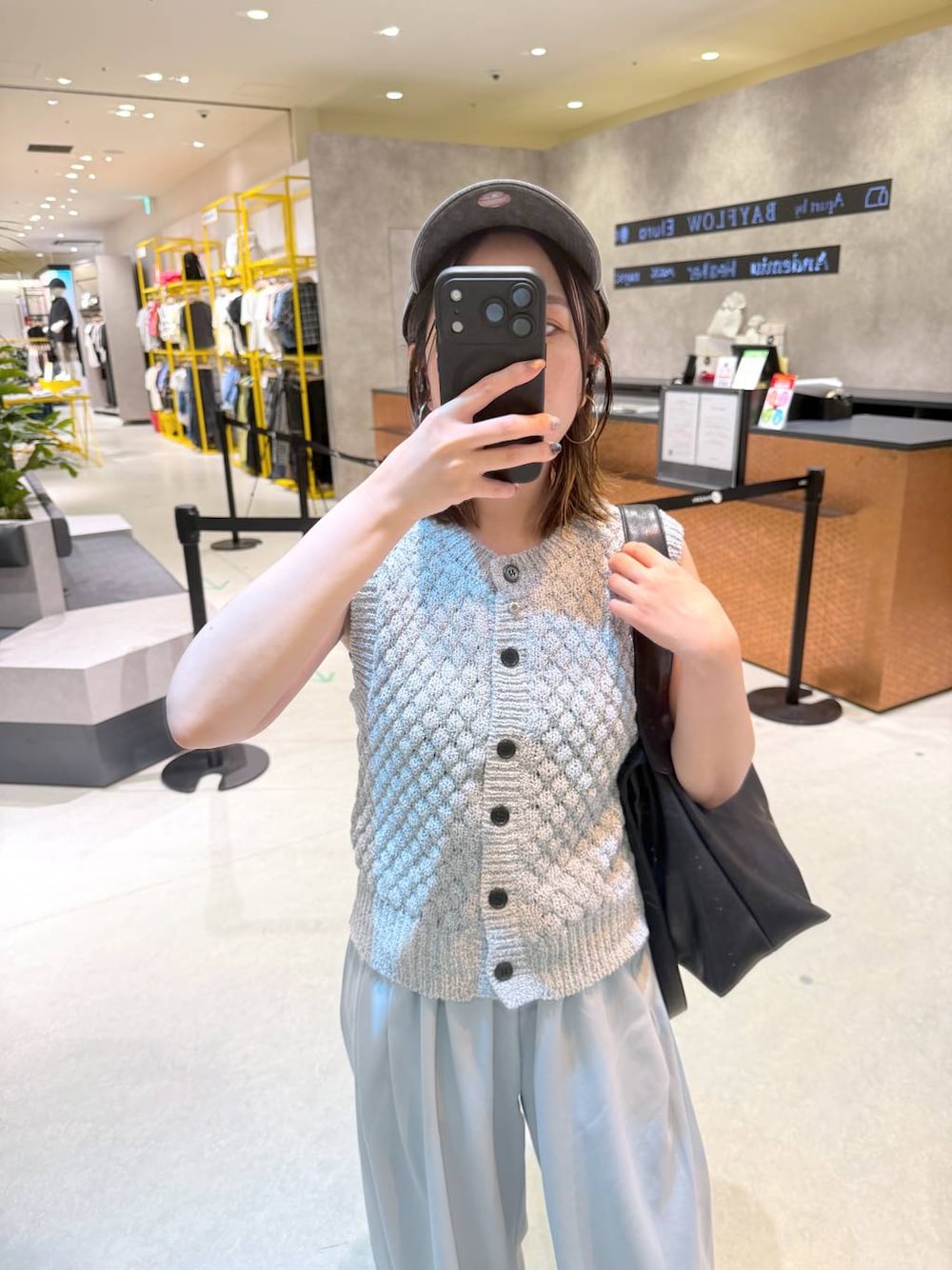 グレー系のベスト、ブラック系のショルダーバッグ、ブルー系のスウェットパンツを着用したレディースの夏コーディネートの1枚目の写真