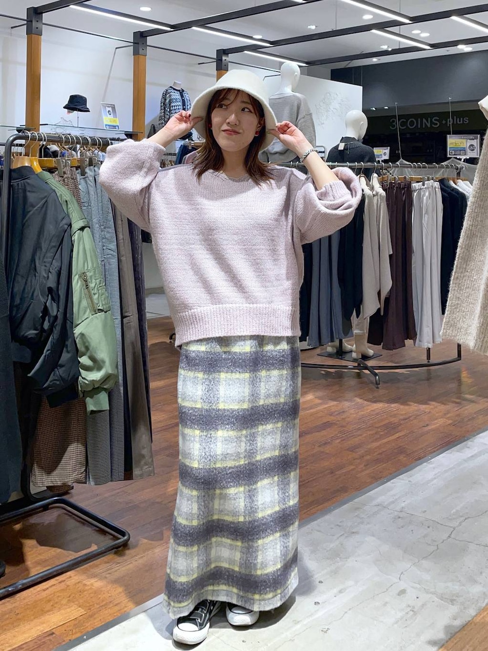 グレー系のスカート、ピンク系のニット/セーター、ホワイト系のハットを着用したレディースの冬コーディネートの1枚目の写真