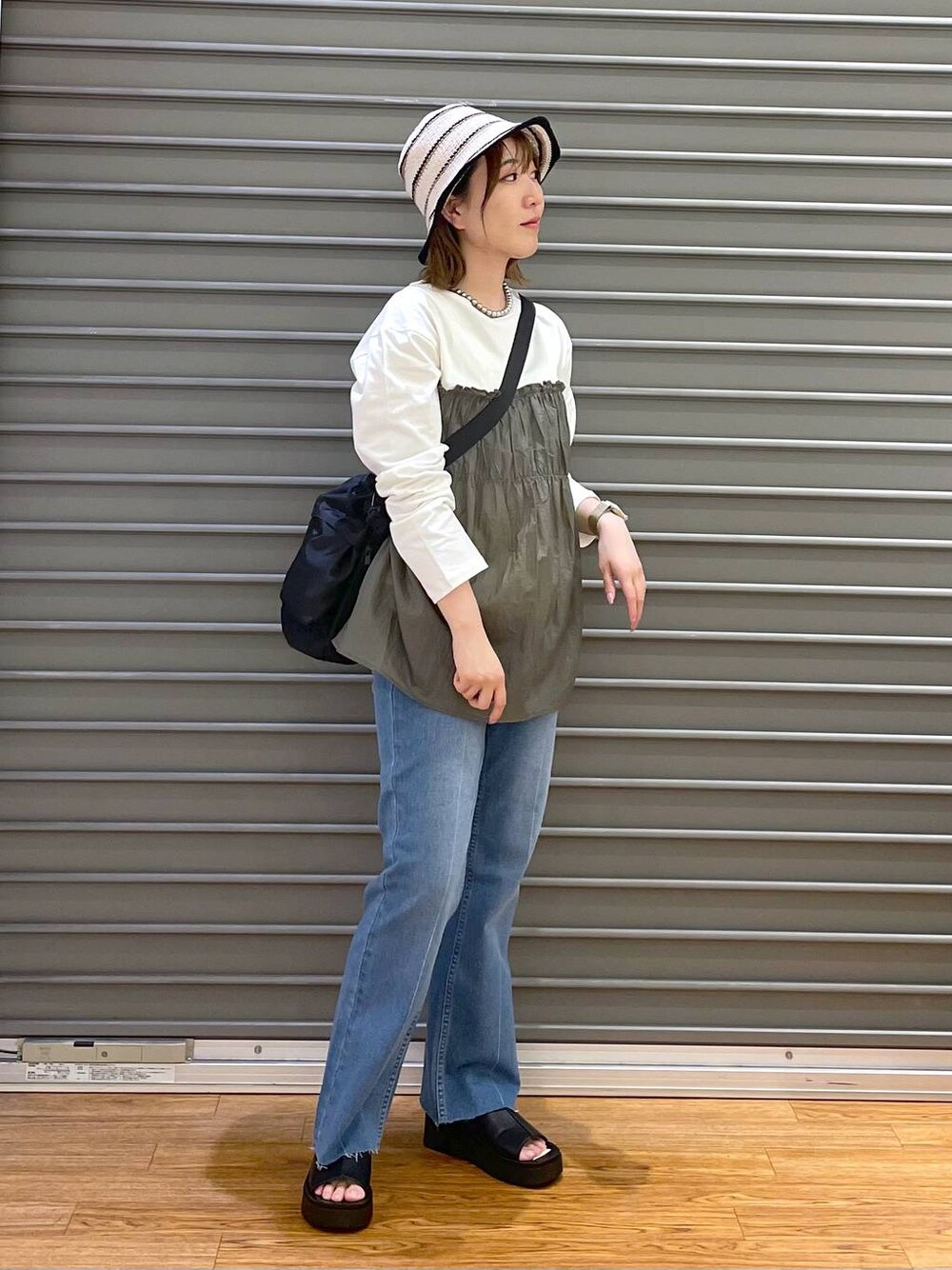 グリーン系のTシャツ/カットソー、ブラック系のショルダーバッグ、ブルー系のデニムパンツを着用したレディースの春コーディネートの1枚目の写真