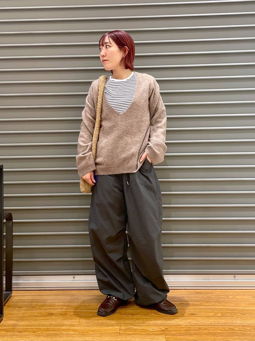 ブラウン系のニット/セーター、グレー系のその他パンツ、ゴールド系のショルダーバッグを着用したレディースの冬コーディネートの1枚目の写真