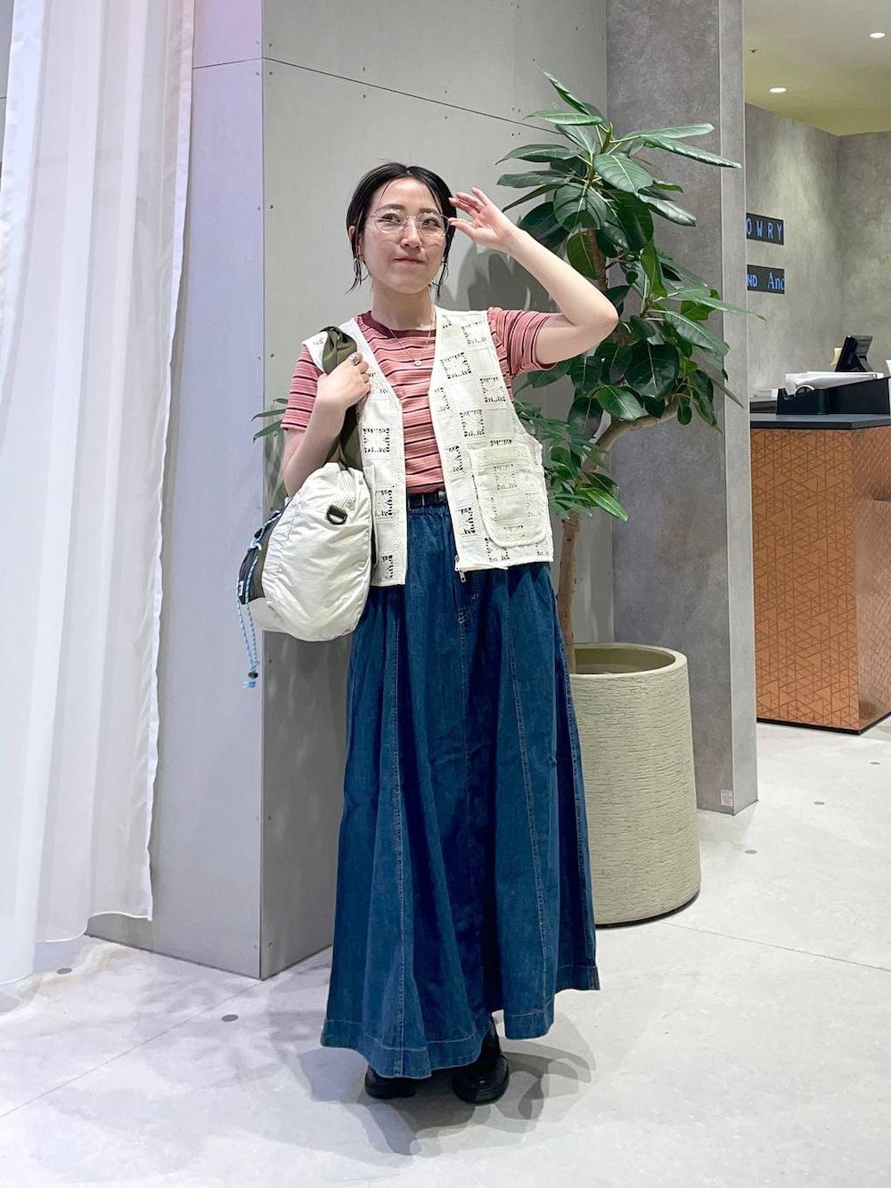 オレンジ系のTシャツ/カットソー、ブルー系のスカート、ベージュ系のボストンバッグを着用したレディースの春コーディネートの1枚目の写真