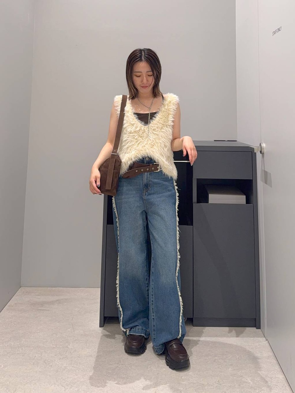 ブルー系のデニムパンツ、ベージュ系のベスト、ブラウン系のローファーを着用したレディースの夏コーディネートの1枚目の写真