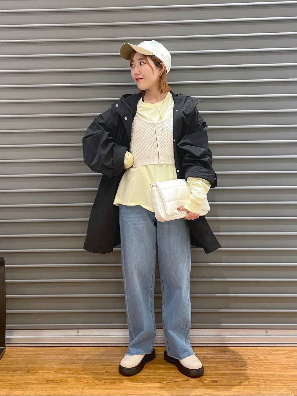 ホワイト系のショルダーバッグ、ホワイト系のニット/セーター、ブルー系のデニムパンツを着用したレディースの春コーディネートの1枚目の写真