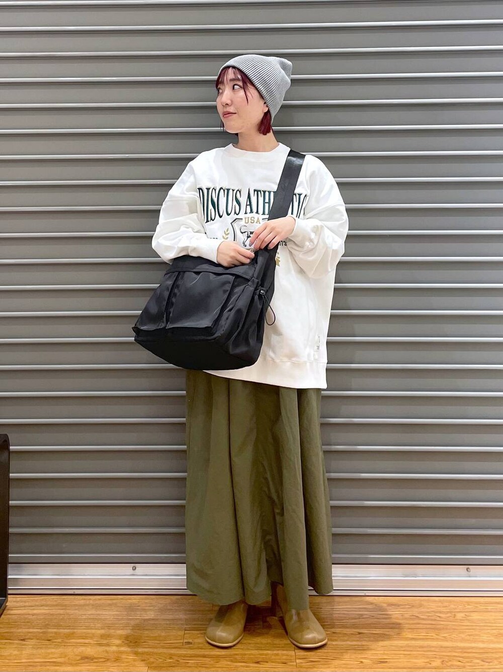 ホワイト系のスウェット、ブラウン系のブーツ、グリーン系のスカートを着用したレディースの冬コーディネートの1枚目の写真