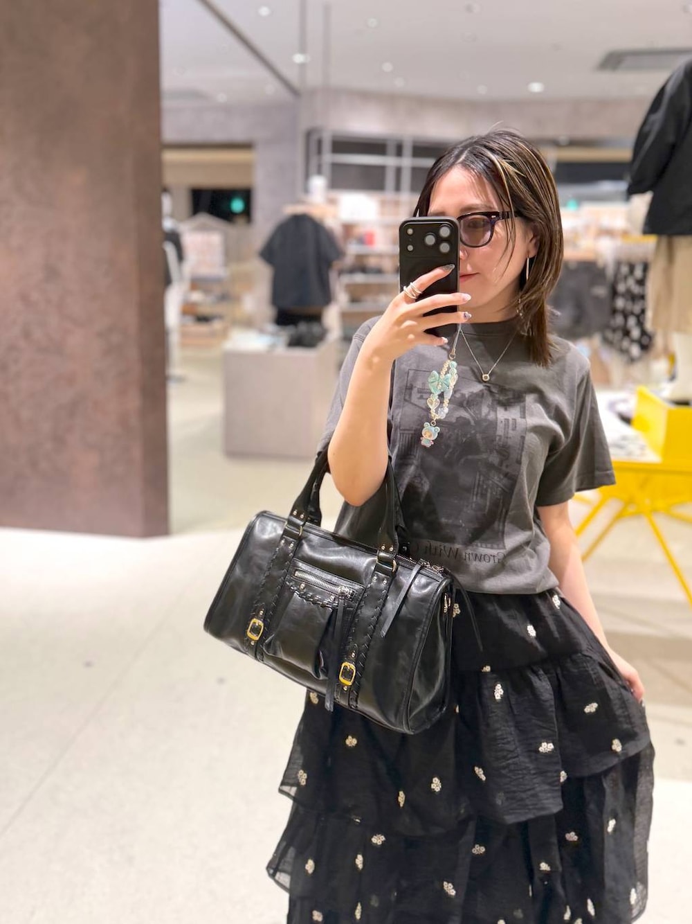 ブラック系のボストンバッグ、ブラック系のスカート、ブラック系のTシャツ/カットソーを着用したレディースの夏コーディネートの1枚目の写真