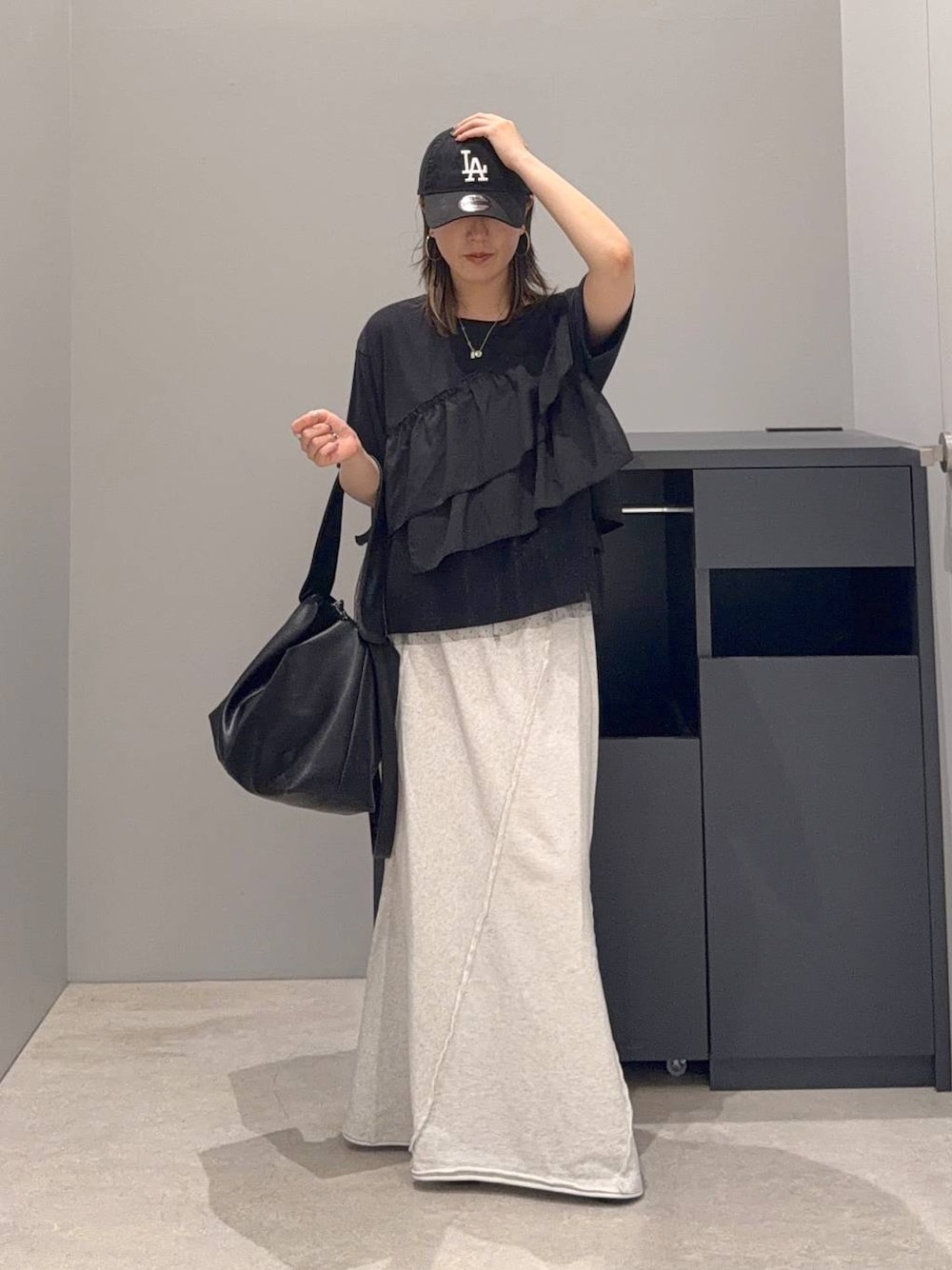 グレー系のスカート、ブラック系のショルダーバッグ、ブラック系のTシャツ/カットソーを着用したレディースの夏コーディネートの1枚目の写真