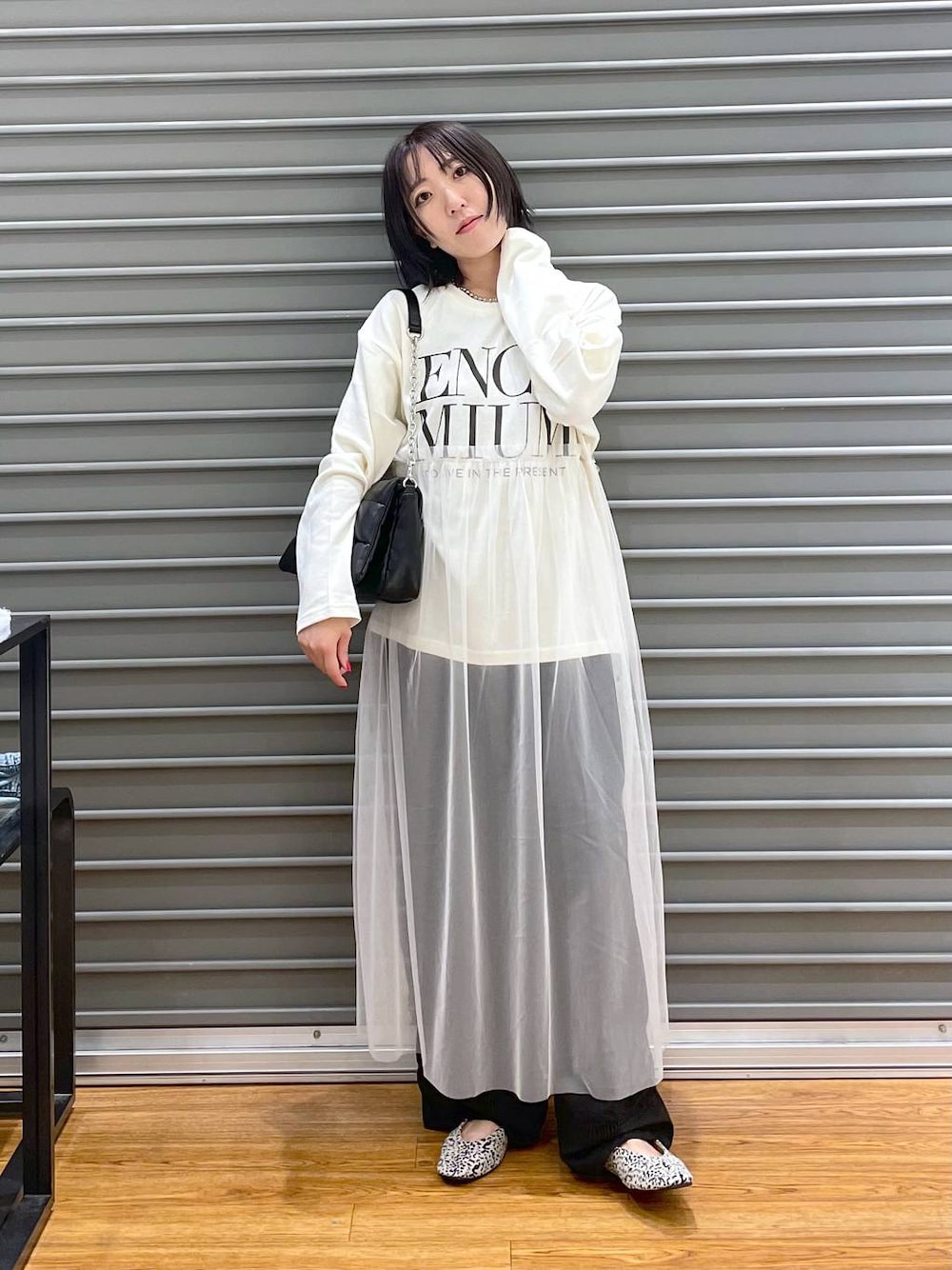 ブラック系のショルダーバッグ、グレー系のチノパンツ、ホワイト系のパンプスを着用したレディースの秋コーディネートの1枚目の写真