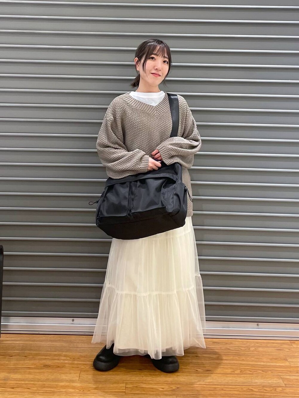 ホワイト系のスカート、ブラウン系のニット/セーター、ホワイト系のTシャツ/カットソーを着用したレディースの春コーディネートの1枚目の写真