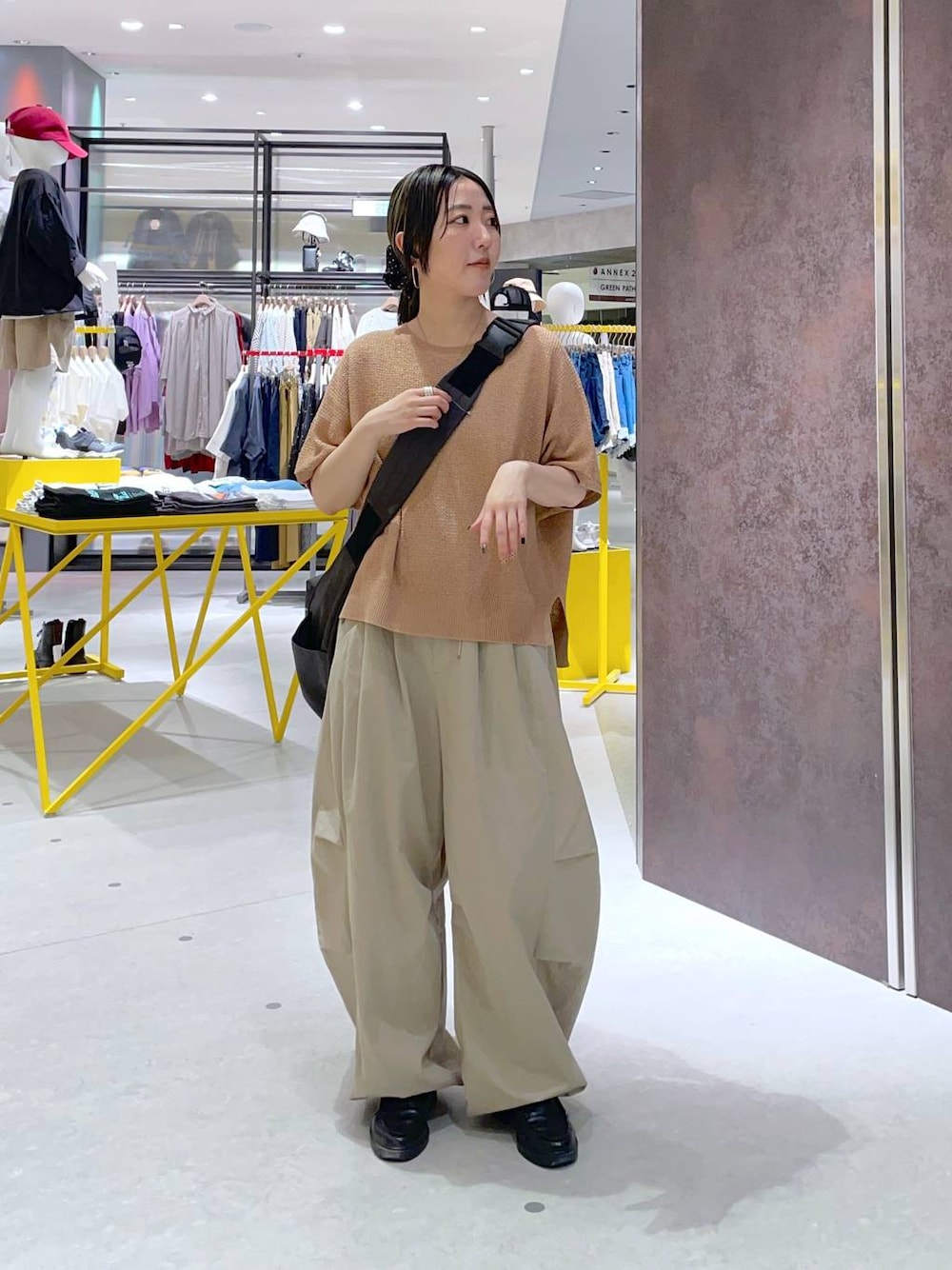 グレー系のショルダーバッグ、オレンジ系のニット/セーター、ベージュ系のその他パンツを着用したレディースの春コーディネートの1枚目の写真
