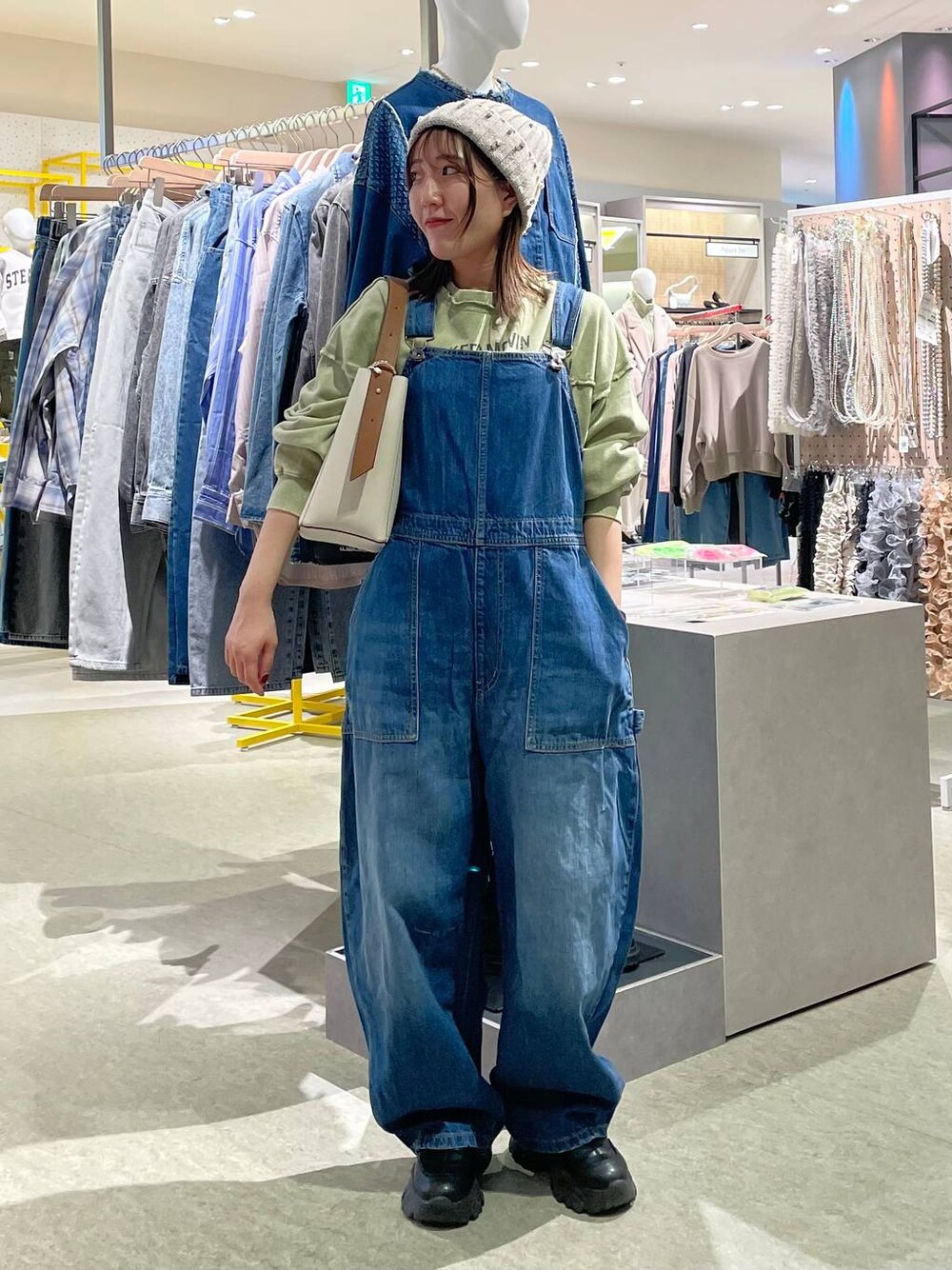 ブルー系のサロペット/オーバーオール、ホワイト系のショルダーバッグ、グリーン系のスウェットを着用したレディースの冬コーディネートの1枚目の写真