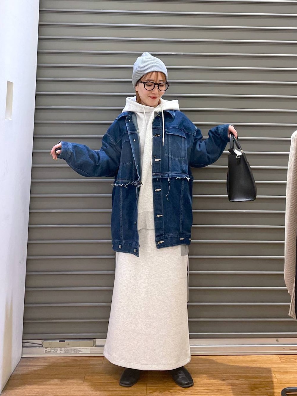 ブルー系のデニムジャケット、グレー系のスカート、ブラック系のショルダーバッグを着用したレディースの冬コーディネートの1枚目の写真