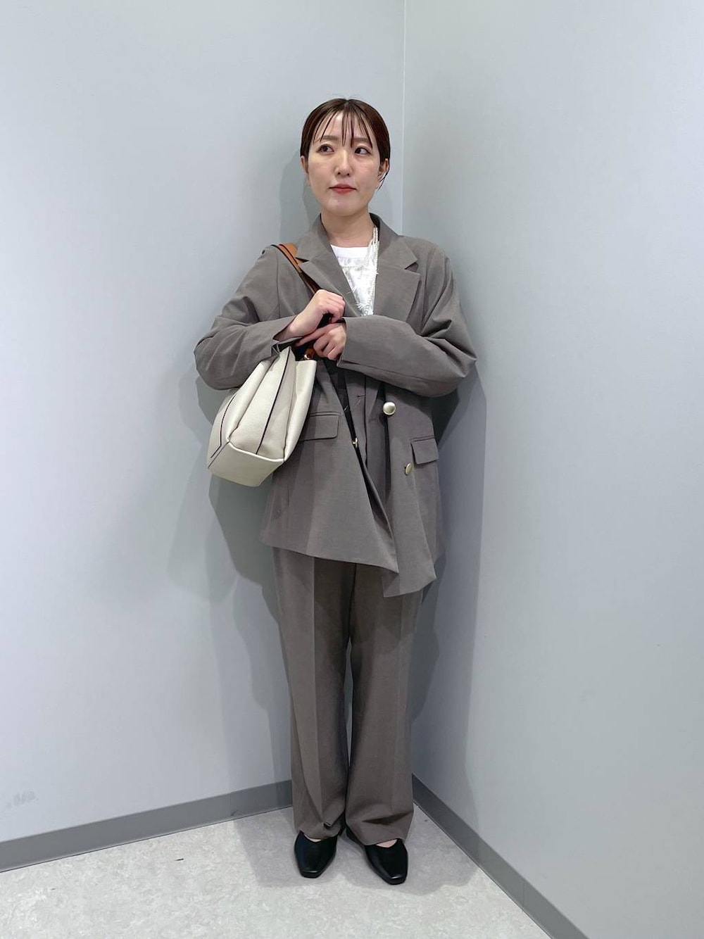 ブラック系のパンプス、ブラウン系のスラックス、ホワイト系のシャツ/ブラウスを着用したレディースの冬コーディネートの1枚目の写真