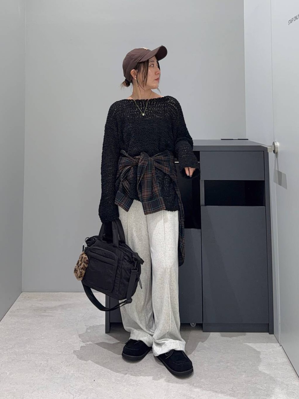 ブラック系のニット/セーター、ブラック系のトートバッグ、ブラック系のモカシン/デッキシューズを着用したレディースの秋コーディネートの1枚目の写真