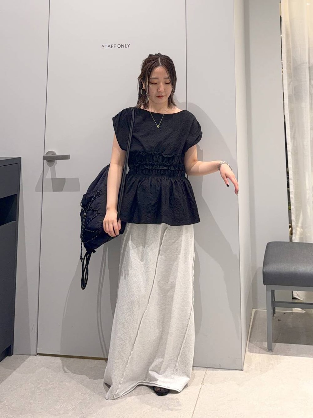 グレー系のスカート、ブラック系のバックパック/リュック、ブラック系のシャツ/ブラウスを着用したレディースの夏コーディネートの1枚目の写真