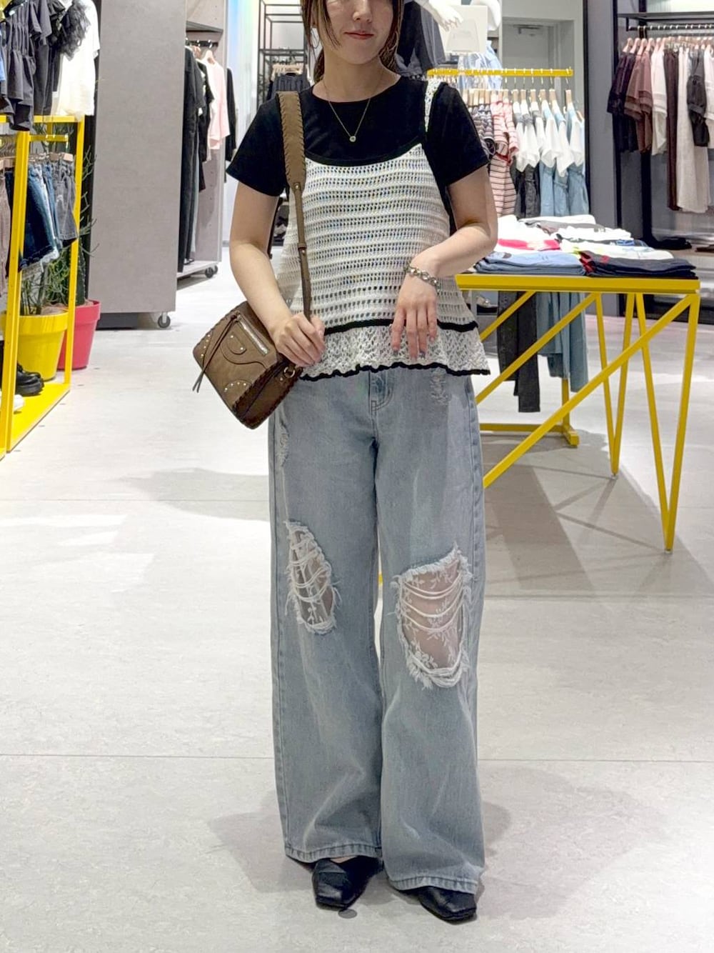 ブルー系のデニムパンツ、ブラック系のTシャツ/カットソー、ブラウン系のショルダーバッグを着用したレディースの夏コーディネートの1枚目の写真