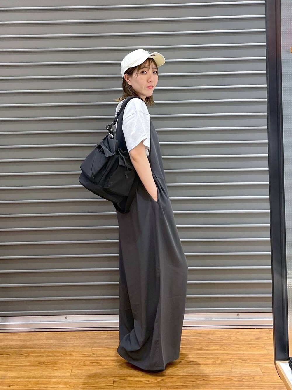 ブラック系のショルダーバッグ、ベージュ系のTシャツ/カットソー、グレー系のサロペット/オーバーオールを着用したレディースの夏コーディネートの1枚目の写真