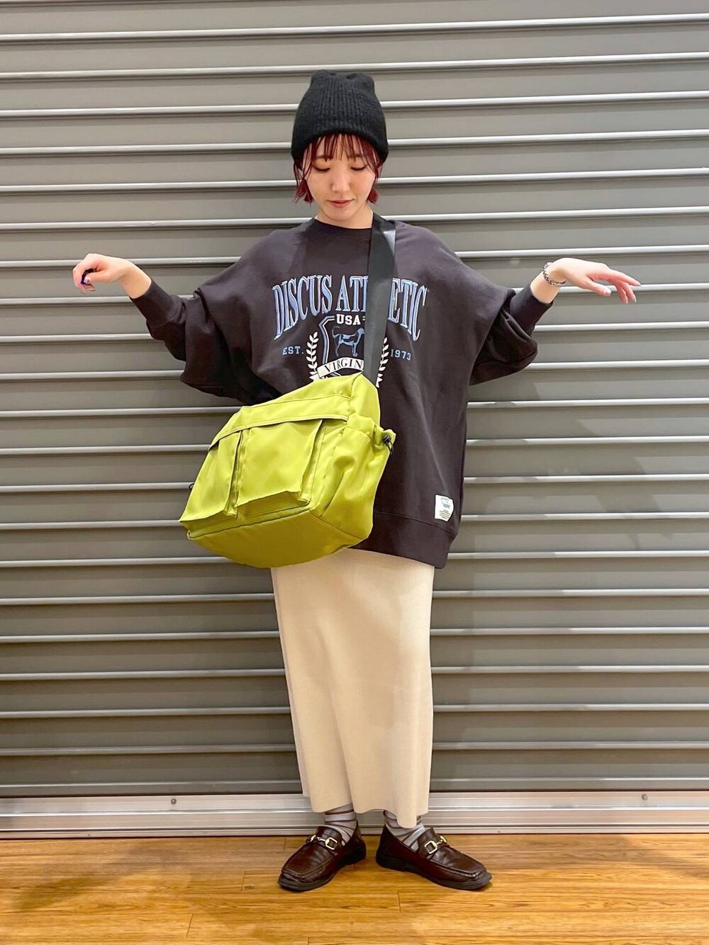 ホワイト系のスカート、グレー系のスウェット、グリーン系のショルダーバッグを着用したレディースの冬コーディネートの1枚目の写真