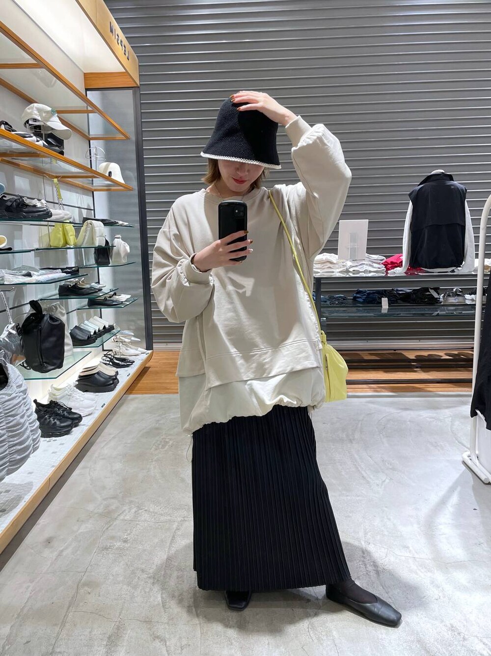 イエロー系のショルダーバッグ、ブラック系のスカート、ベージュ系のTシャツ/カットソーを着用したレディースの春コーディネートの1枚目の写真